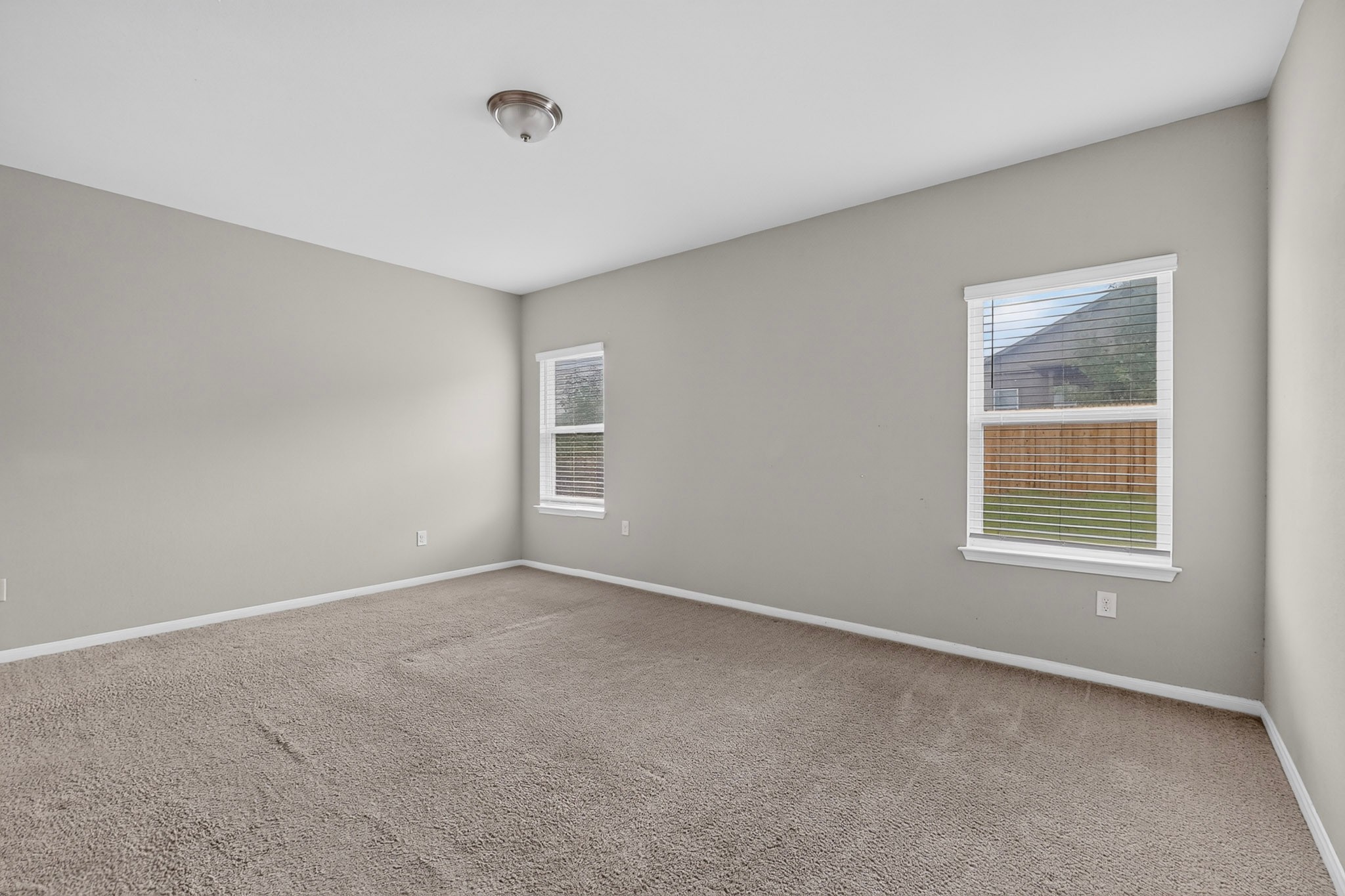 6920 Ranchito Drive Austin, TX 78744 - Photo 3 of 4 An airy bedroom with dual windows and plush carpeting offers a tranquil retreat.