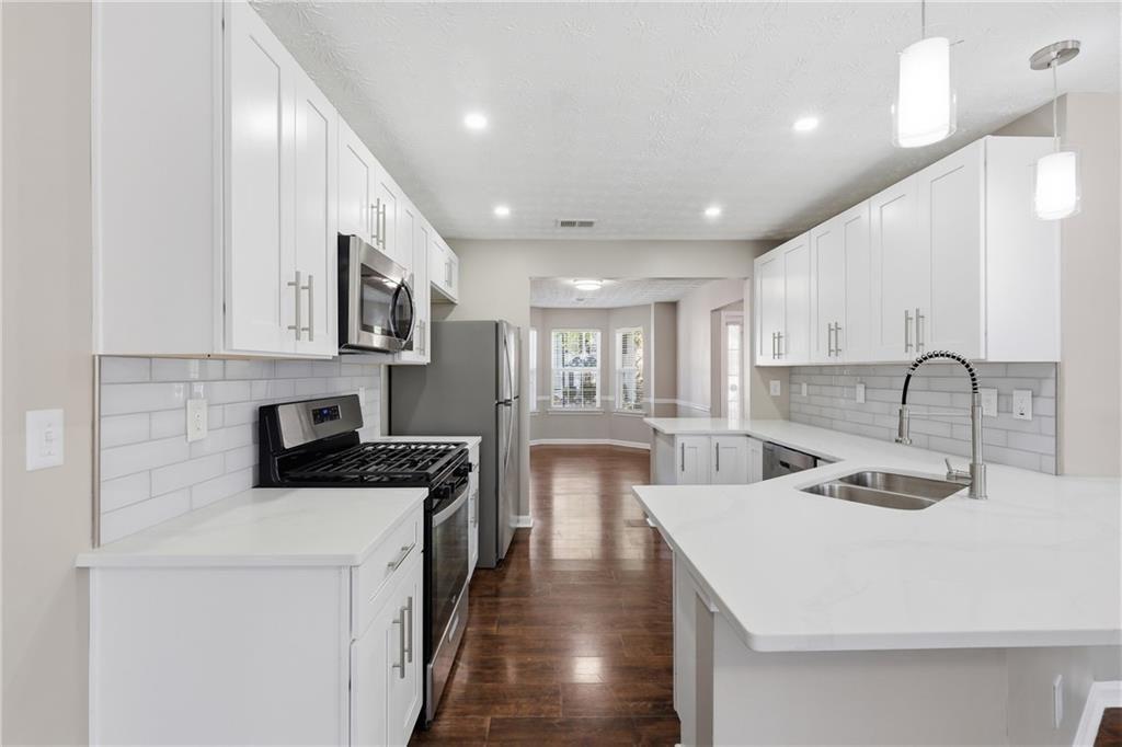 3570 Bogan Mill Road Northeast Buford, GA 30519 - Photo 1 of 31 a kitchen with stainless steel appliances a sink a stove a refrigerator cabinets and a dining table