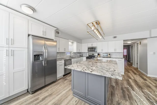a kitchen with stainless steel appliances granite countertop a sink stove and refrigerator