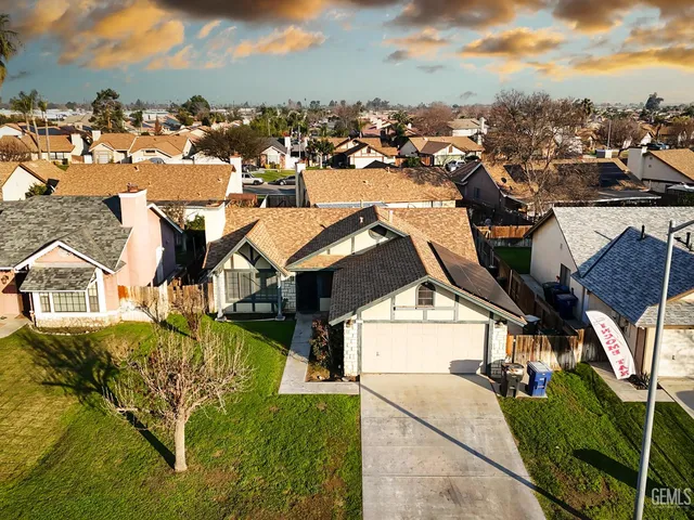 an aerial view of residential houses with outdoor space and trees