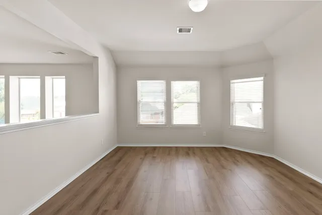 an empty room with wooden floor and windows
