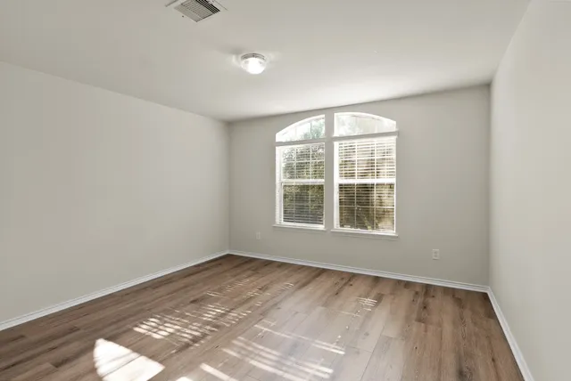 an empty room with wooden floor and windows
