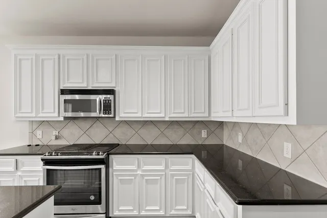 a kitchen with granite countertop white cabinets and stainless steel appliances