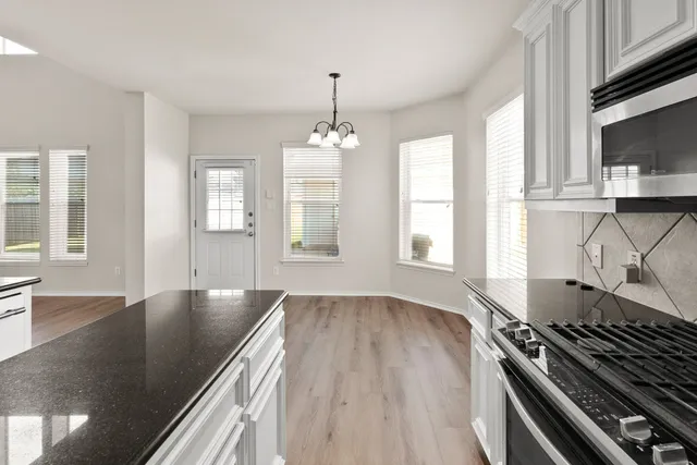 a kitchen with granite countertop a stove a sink and wooden floor