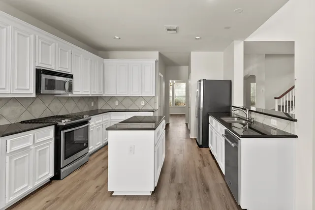 a kitchen with stainless steel appliances granite countertop a stove top oven a sink and a refrigerator