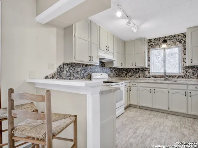 a kitchen with stainless steel appliances granite countertop a stove a sink and white cabinets