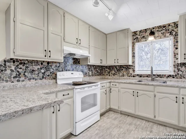 a kitchen with granite countertop white cabinets and white appliances