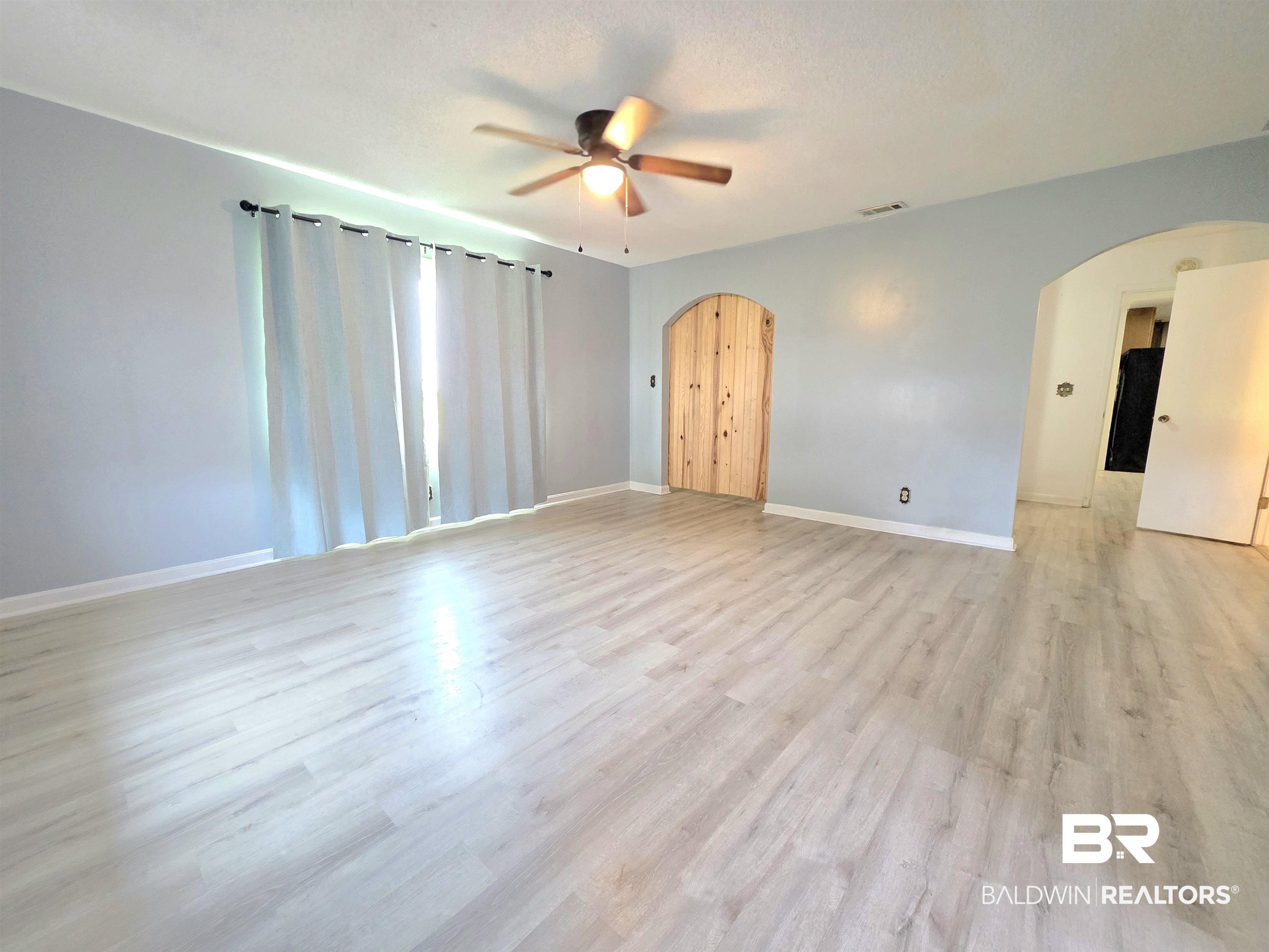 558 Stanton Road Atmore, AL 36502 - Photo 8 of 29 Spacious room featuring light wood-finish flooring, light blue wall paint, and white baseboards