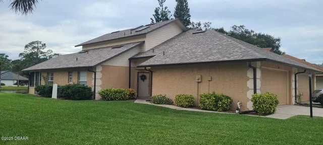 a view of a house with a yard and palm trees
