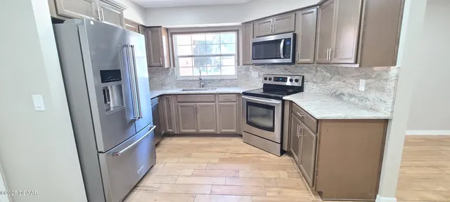 a kitchen with stainless steel appliances granite countertop a refrigerator stove and sink