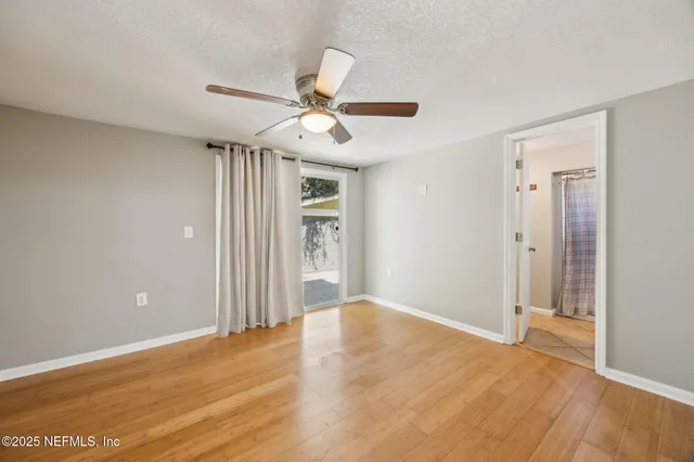 a view of empty room with wooden floor and fan