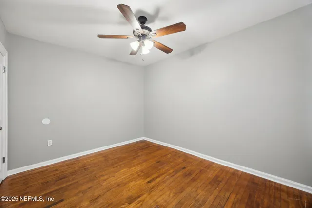 an empty room with a ceiling fan and wooden floor