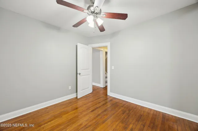 an empty room with wooden floor chandelier fan and closet area