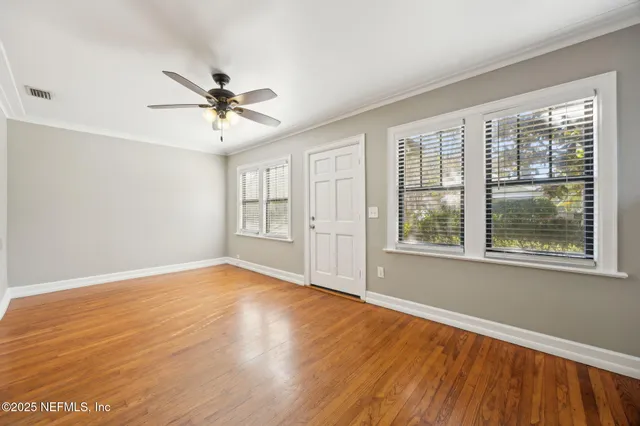a view of empty room with wooden floor and fan
