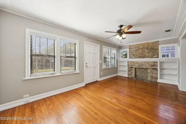 a view of an empty room with a window and wooden floor