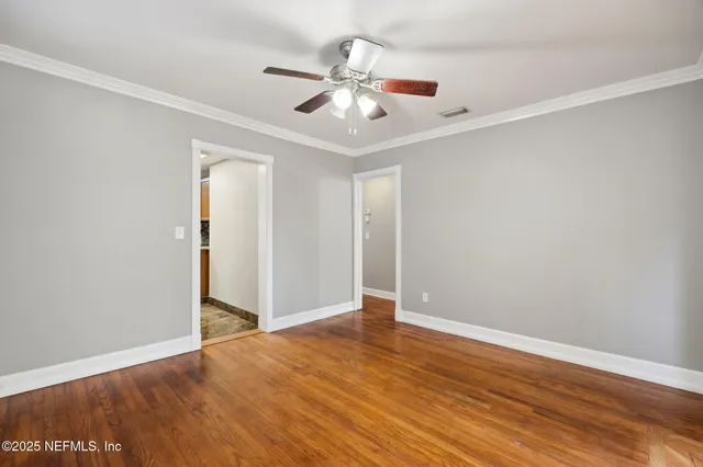 an empty room with wooden floor fan and windows