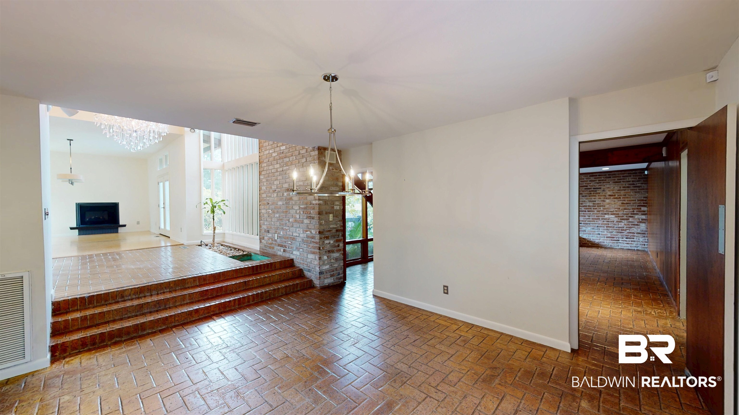 15 Spring Bank Road Mobile, AL 36608 - Photo 17 of 58 Unfurnished dining area featuring brick flooring, a chandelier, a fireplace, and brick wall