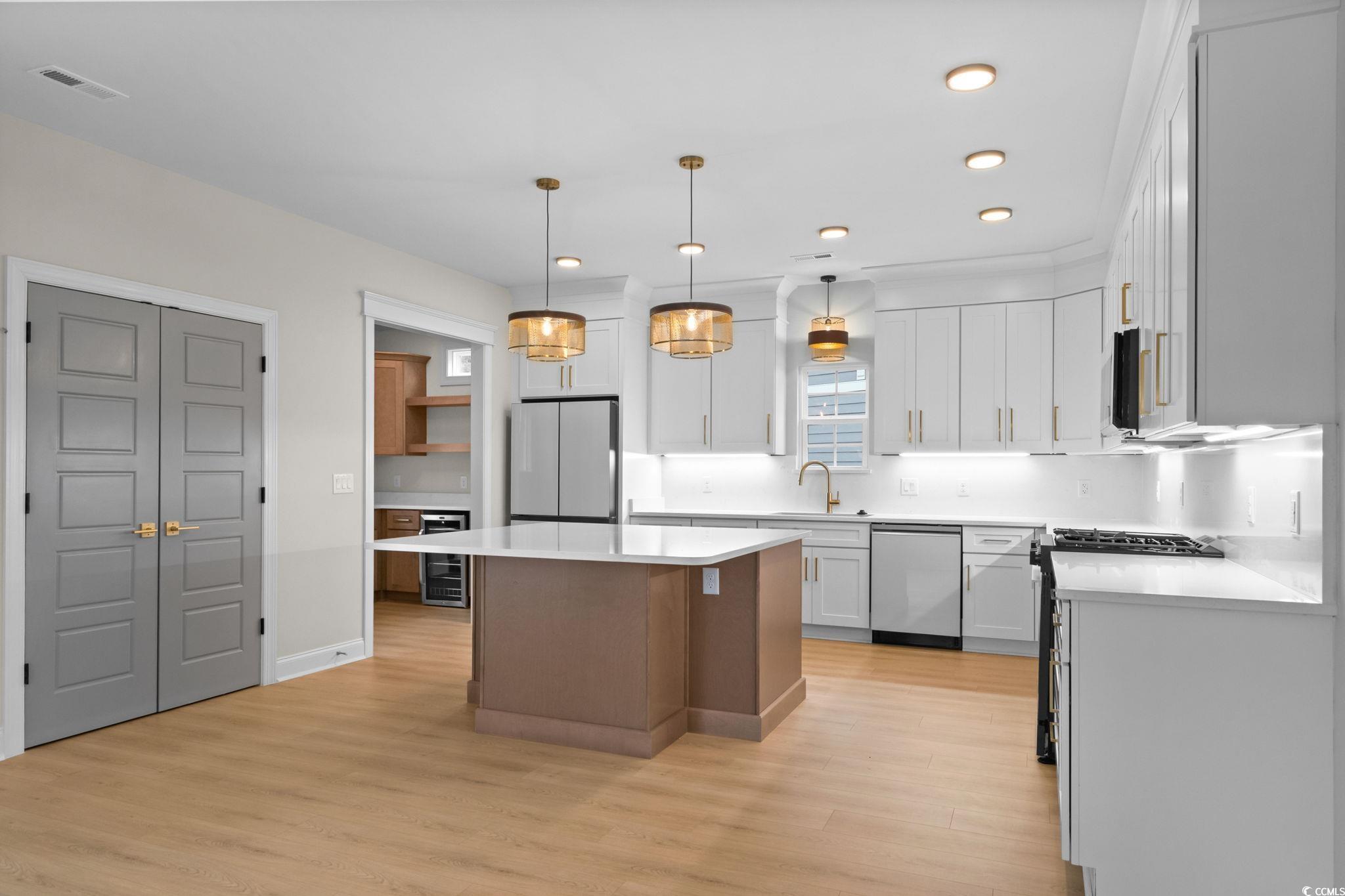 148 Arbor Ridge Circle Conway, SC 29526 - Photo 11 of 37 Kitchen with hanging light fixtures, stainless steel appliances, beverage cooler, white cabinets, and light wood-style floors