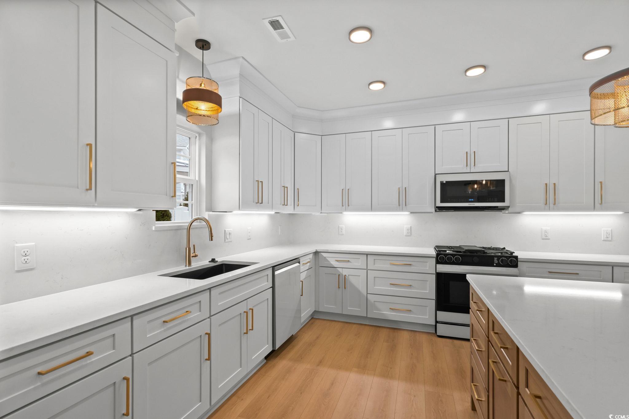 148 Arbor Ridge Circle Conway, SC 29526 - Photo 15 of 37 Kitchen with pendant lighting, gas stove, white cabinets, light wood finished floors, and white microwave