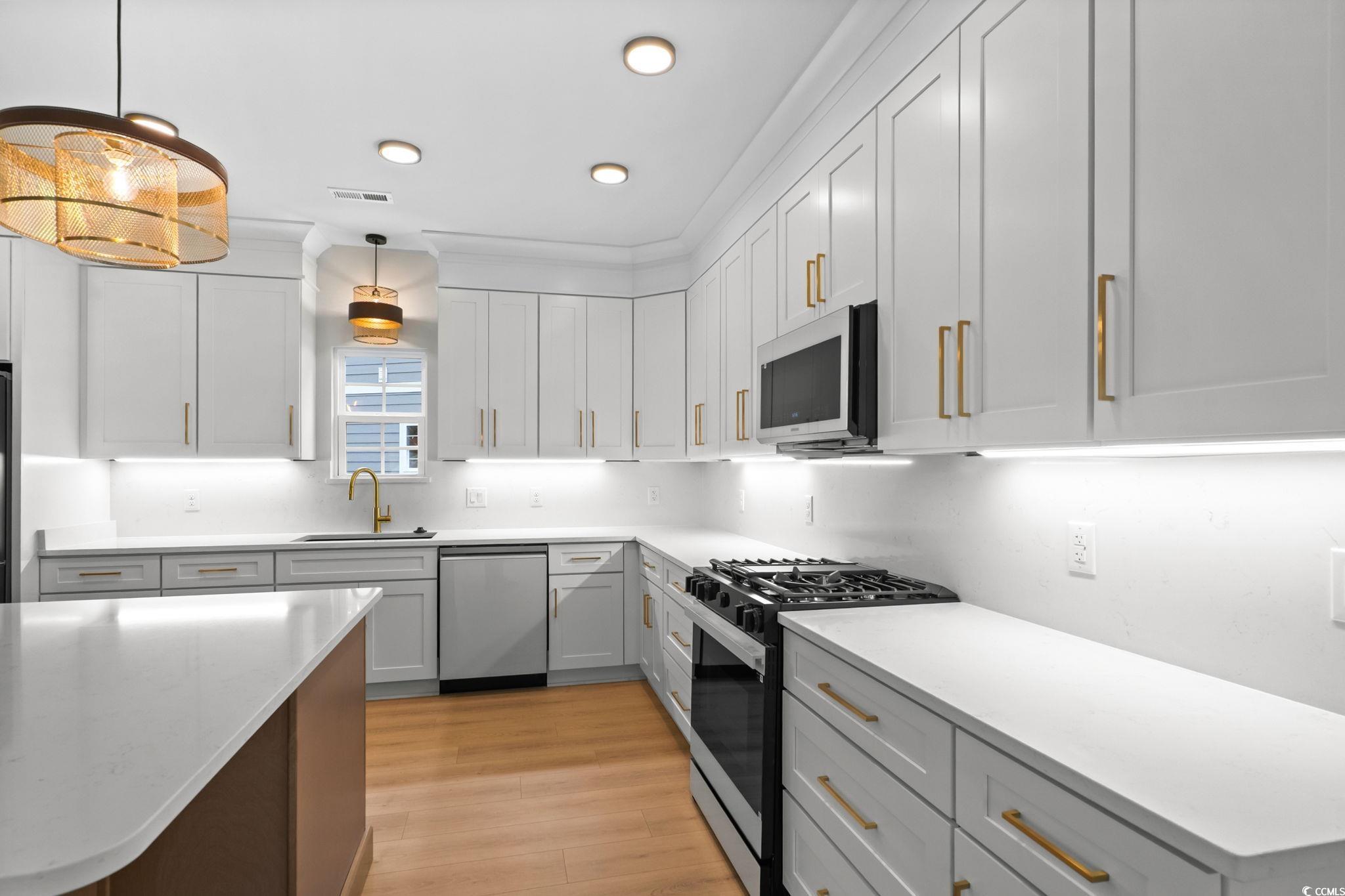148 Arbor Ridge Circle Conway, SC 29526 - Photo 17 of 37 Kitchen featuring stainless steel appliances, decorative light fixtures, light stone countertops, light wood finished floors, and white cabinetry