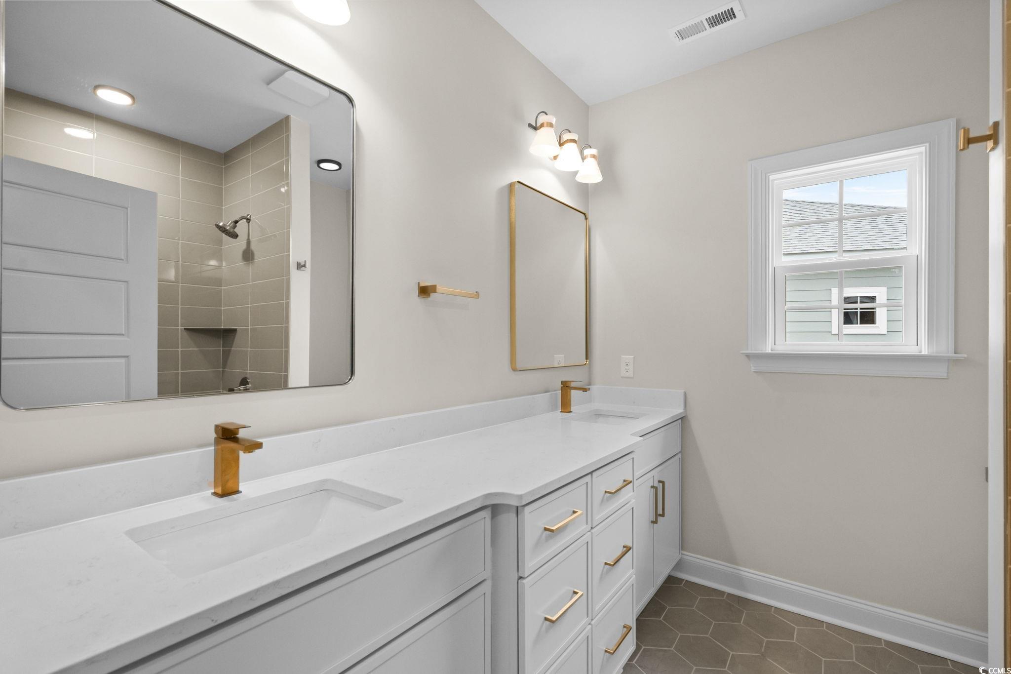 148 Arbor Ridge Circle Conway, SC 29526 - Photo 33 of 37 Bathroom with double vanity, dark tile patterned flooring, and tiled shower