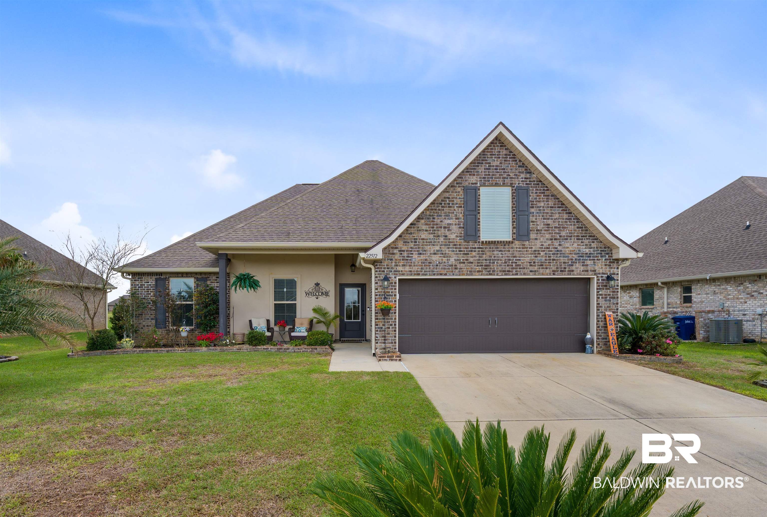 Traditional-style house featuring a front yard, concrete driveway, brick siding, and a garage