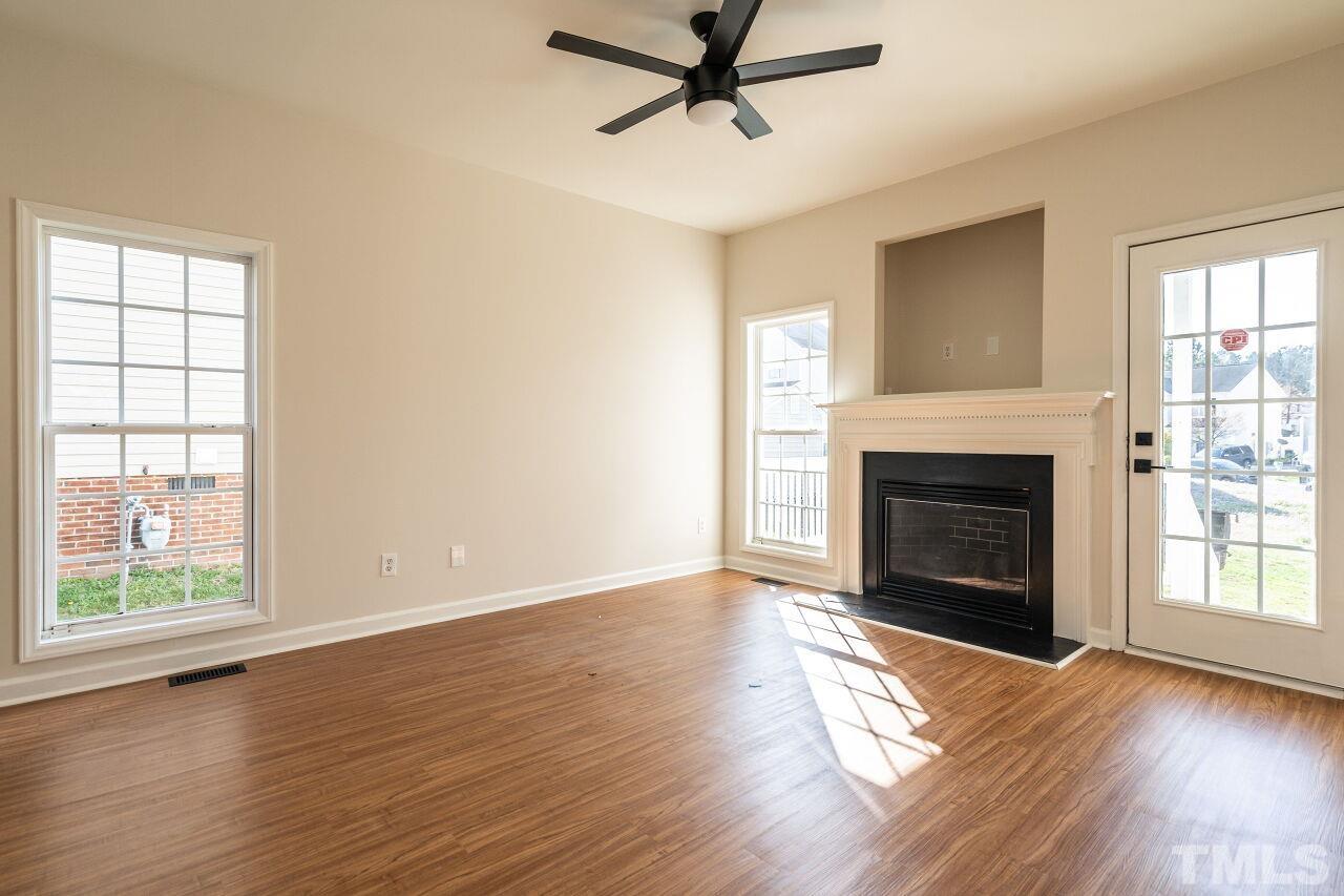 4204 Beacon Crest Way Raleigh, NC 27604 - Photo 8 of 29 an empty room with wooden floor a fireplace and windows