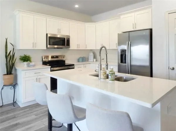 a kitchen with stainless steel appliances a refrigerator a sink a stove a table and chairs