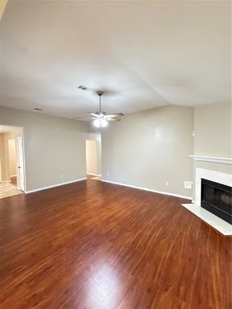 an empty room with wooden floor fireplace and windows