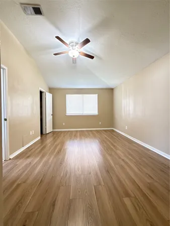 a view of empty room with wooden floor and fan