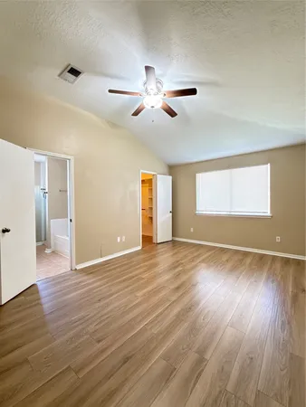 a view of empty room with wooden floor and fan