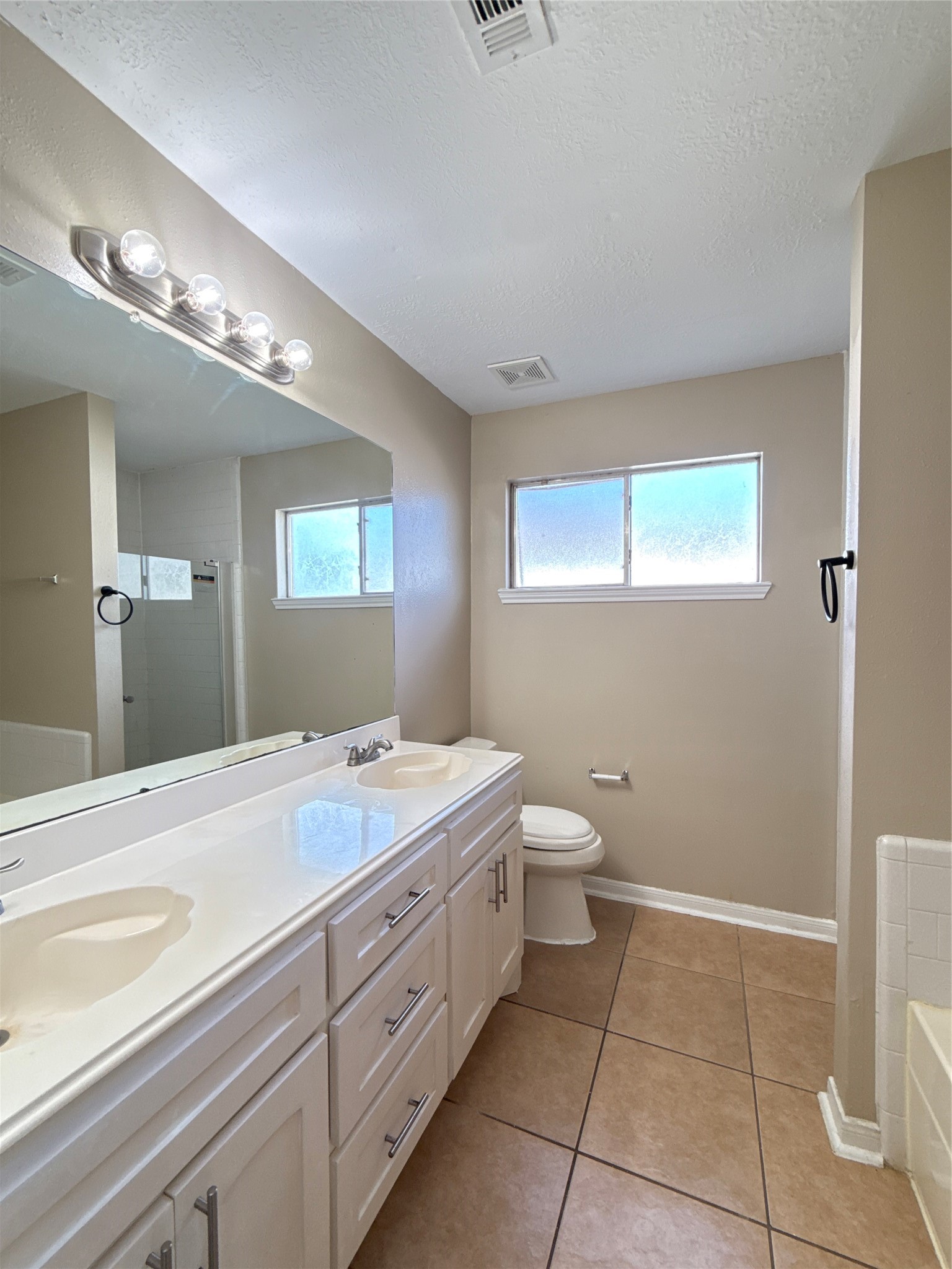 15919 Hiram Clarke Road Houston, TX 77053 - Photo 22 of 29 a spacious bathroom with a granite countertop sink a toilet and a mirror