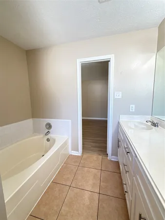 a spacious bathroom with a tub sink and mirror