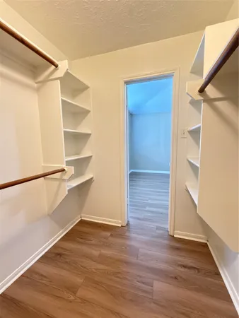 a view of an empty walk in closet with wooden floor