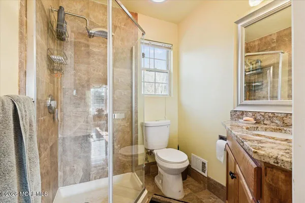 a bathroom with a granite countertop sink a mirror and a shower