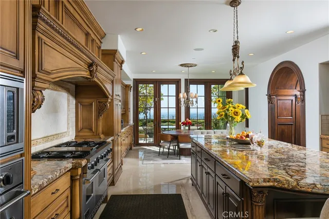 a kitchen with stainless steel appliances granite countertop a stove a sink dishwasher and a dining table with wooden floor