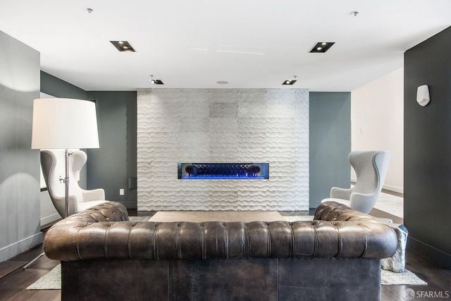 a living room with furniture kitchen view and a wooden floor