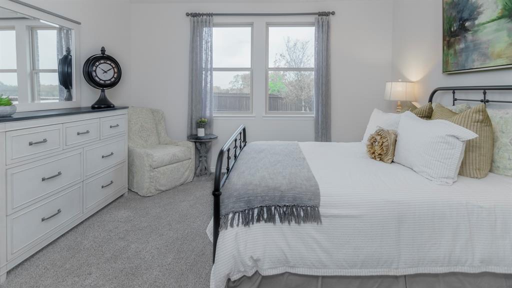 410 Range Road Caddo Mills, TX 75135 - Photo 16 of 19 Carpeted room featuring a white paneled dresser with dark hardware, a pair of windows with drapes, and a metal bed frame