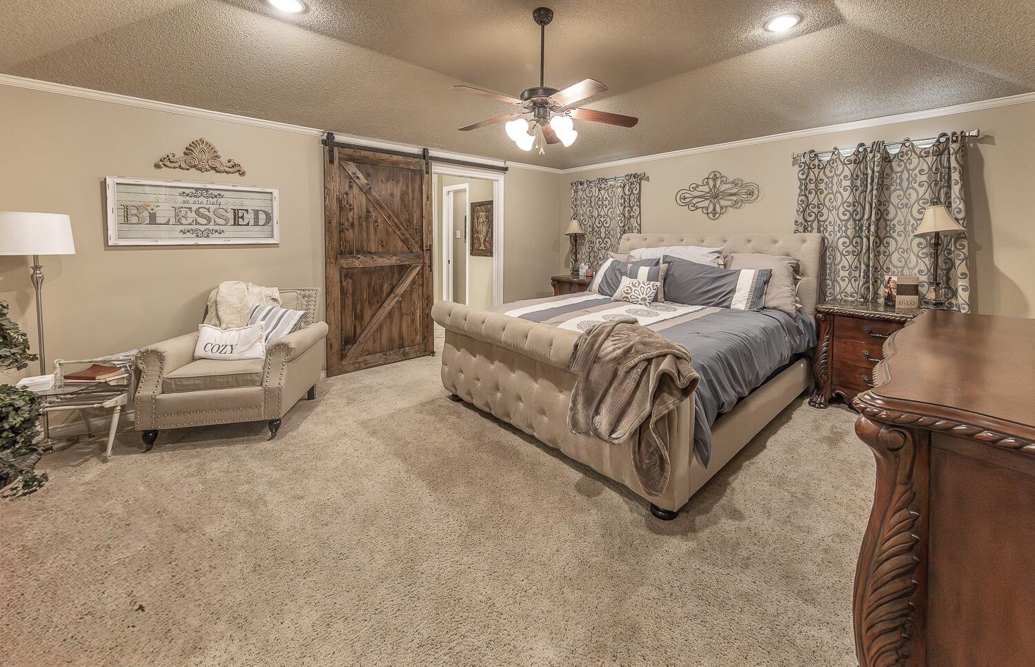 6309 County Road 7470 Lubbock, TX 79424 - Photo 16 of 41 a spacious bedroom with a bed and a chandelier