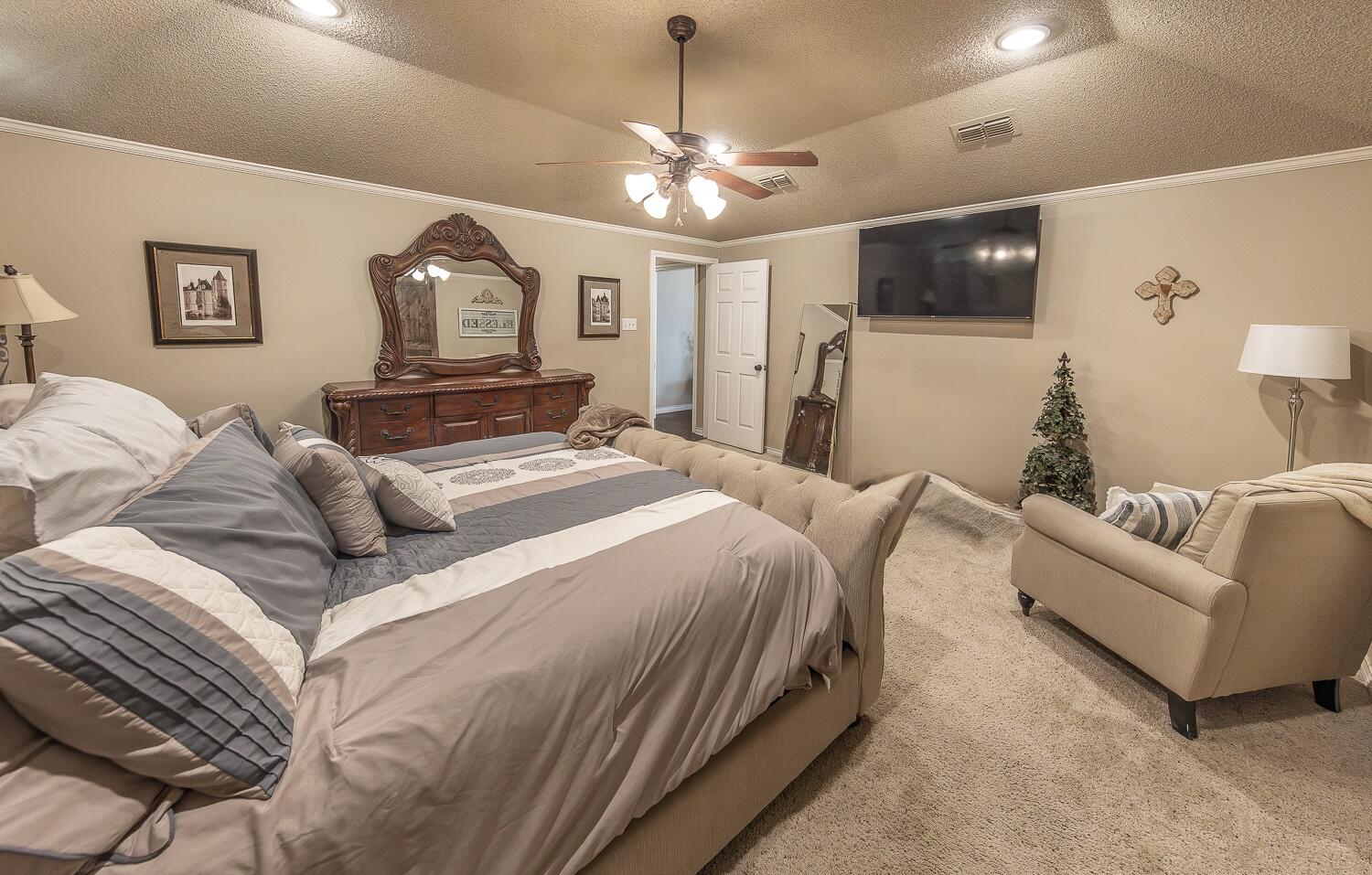 6309 County Road 7470 Lubbock, TX 79424 - Photo 17 of 41 a bedroom with a large bed and a chandelier