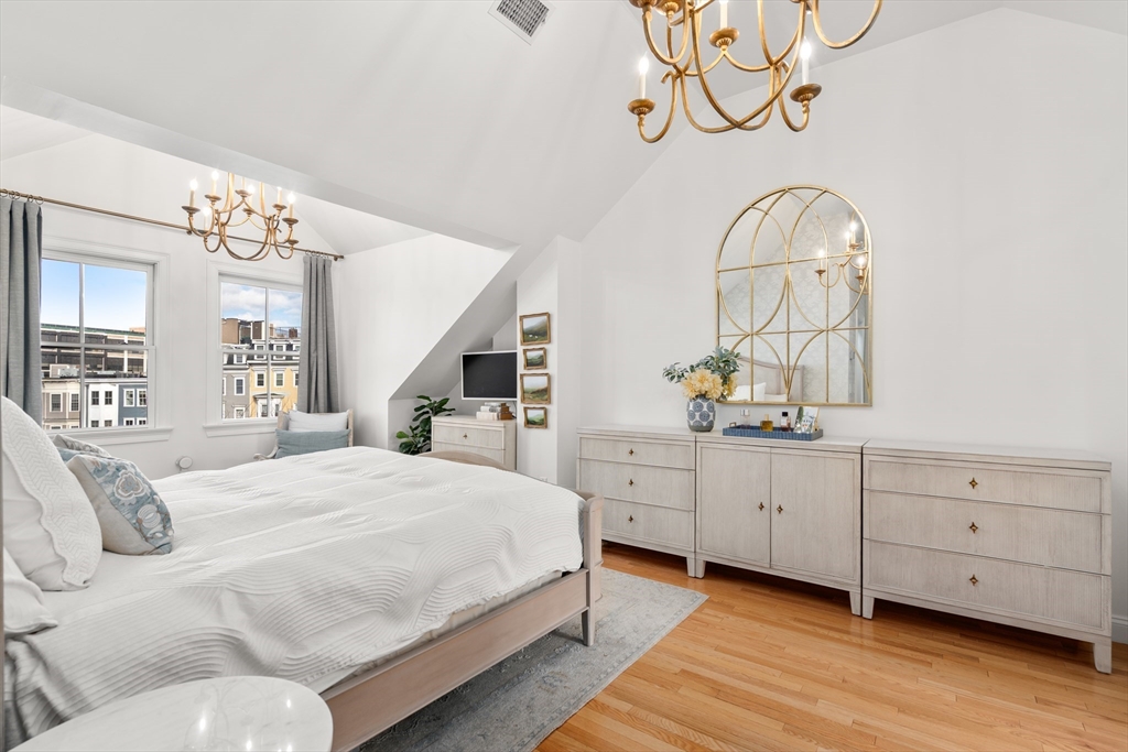 19 Charles Street Boston, MA 02129 - Photo 9 of 28 a spacious bedroom with a large bed and a chandelier