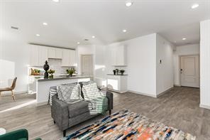 7811 Golden Rubia Lane Rosharon, TX 77583 - Photo 6 of 10 Bright and spacious open-plan living area with modern kitchen, sleek white cabinetry, hardwood floors, and ample natural light.