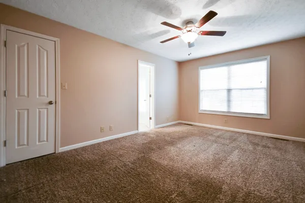 an empty room with windows and ceiling fan