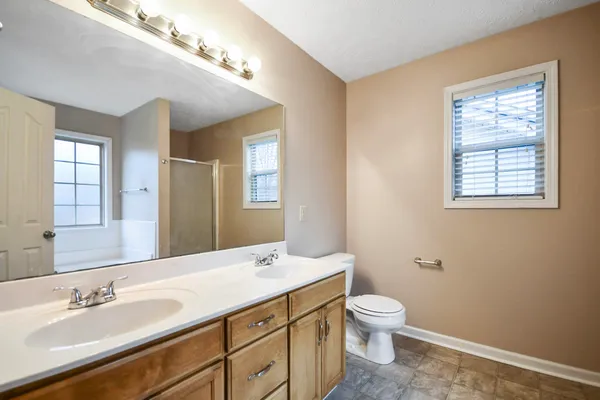a bathroom with a granite countertop toilet a sink a mirror and a window