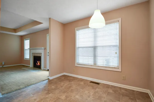 an empty room with windows and fireplace