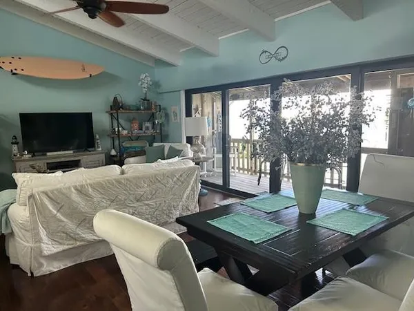 a living room with dining table a flat screen tv and a large window