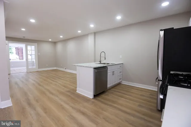 a room with a sink wooden floor and a view of kitchen