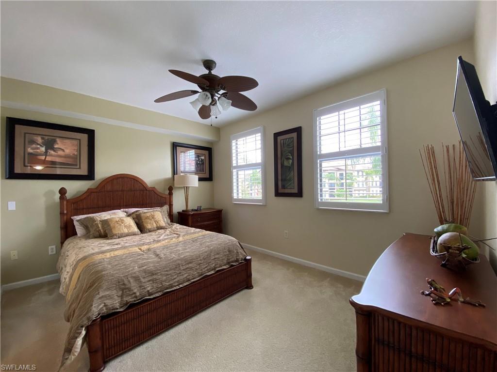 12940 Positano Circle, Unit 204 Naples, FL 34105 - Photo 17 of 39 a bedroom with a bed chandelier and a window