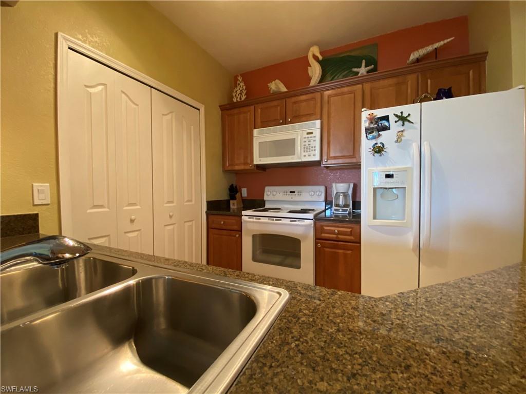 12940 Positano Circle, Unit 204 Naples, FL 34105 - Photo 2 of 39 a kitchen with a refrigerator sink and white stove