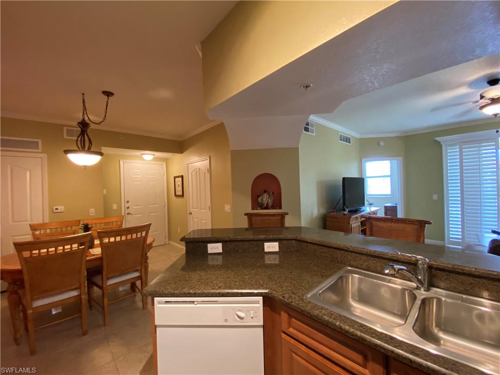 12940 Positano Circle, Unit 204 Naples, FL 34105 - Photo 3 of 39 a kitchen with a sink and chairs